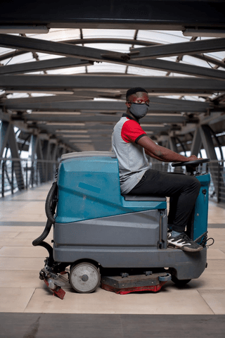 FixIt operator using a ride-on floor scrubber on a pedestrian bridge